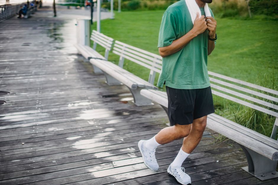 A man in a green shirt goes for a jog on a wooden boardwalk, promoting a healthy lifestyle