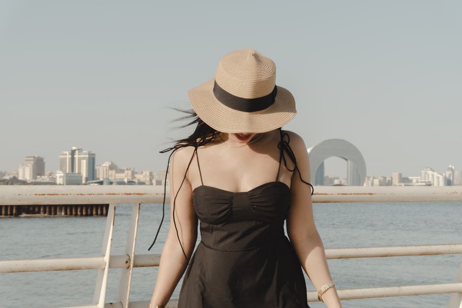 A woman in a sun hat and dress enjoying a sunny day by the sea in Baku, Azerbaijan.
