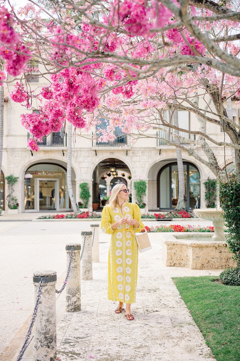 Woman carrying a structured Boo rattan tote on a sunny garden walkway