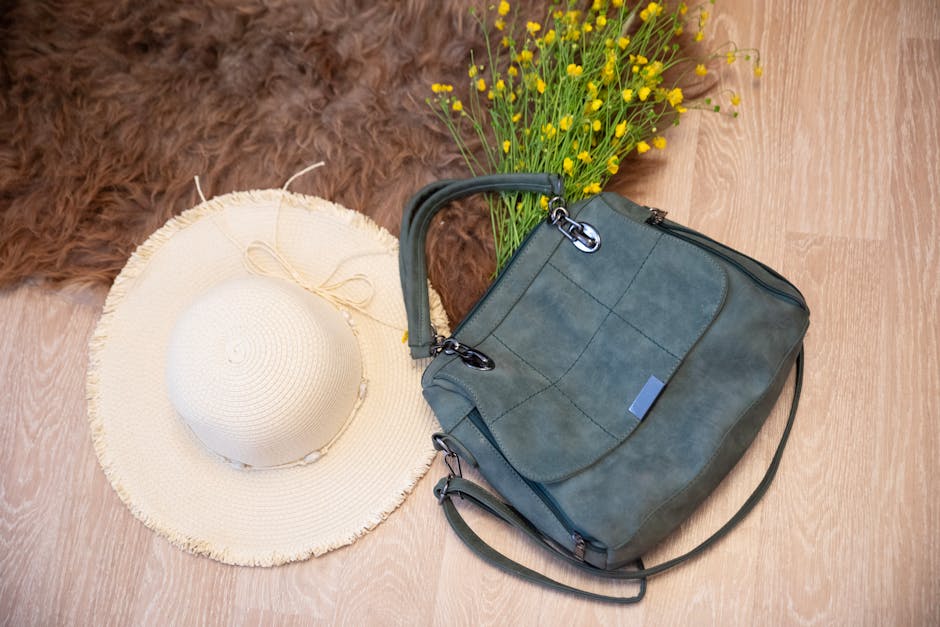 Flat lay of a summer hat and a stylish tote bag with flowers on a wooden floor.