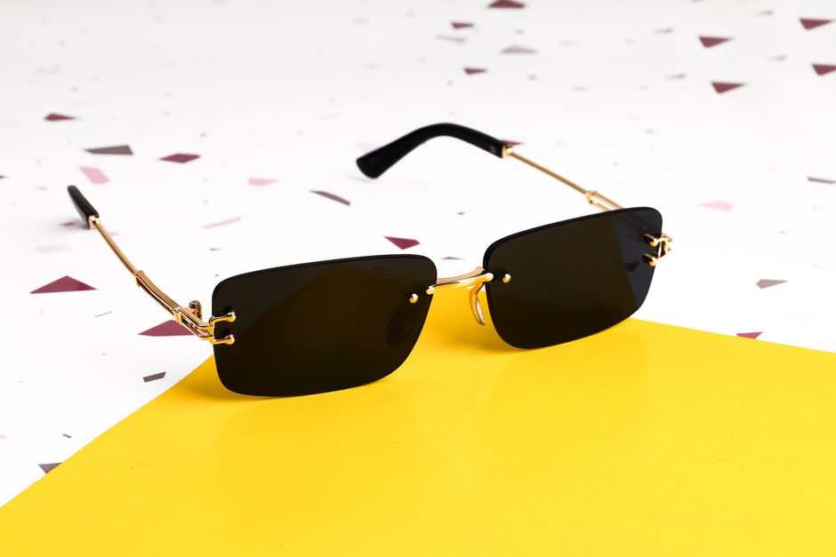 Elegant black sunglasses with gold accents on a vibrant yellow background.
