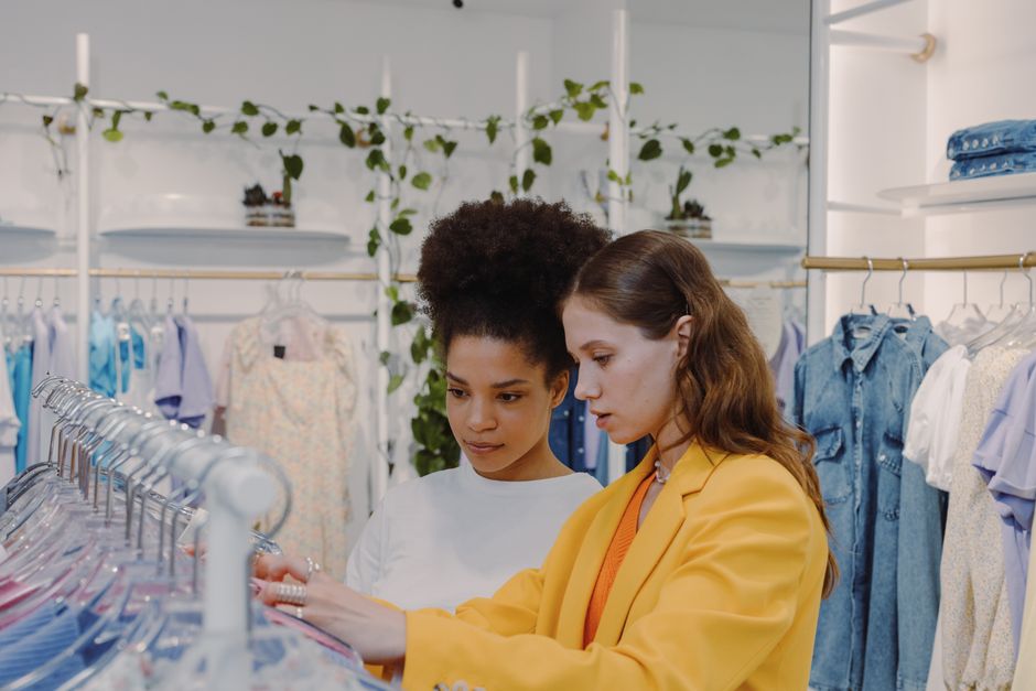 Stylish women shopping and choosing outfits in a modern boutique setting.