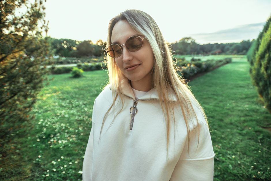 Young woman wearing sunglasses enjoying a peaceful moment in a sunny park.