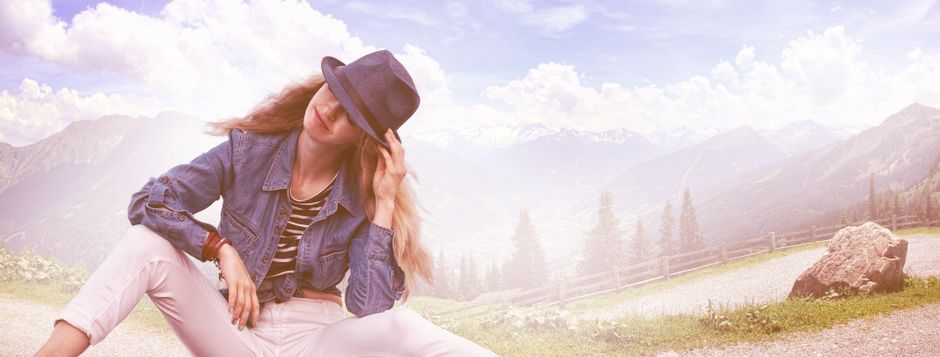 A woman in a casual chic outfit poses outdoors with a stunning mountain backdrop.