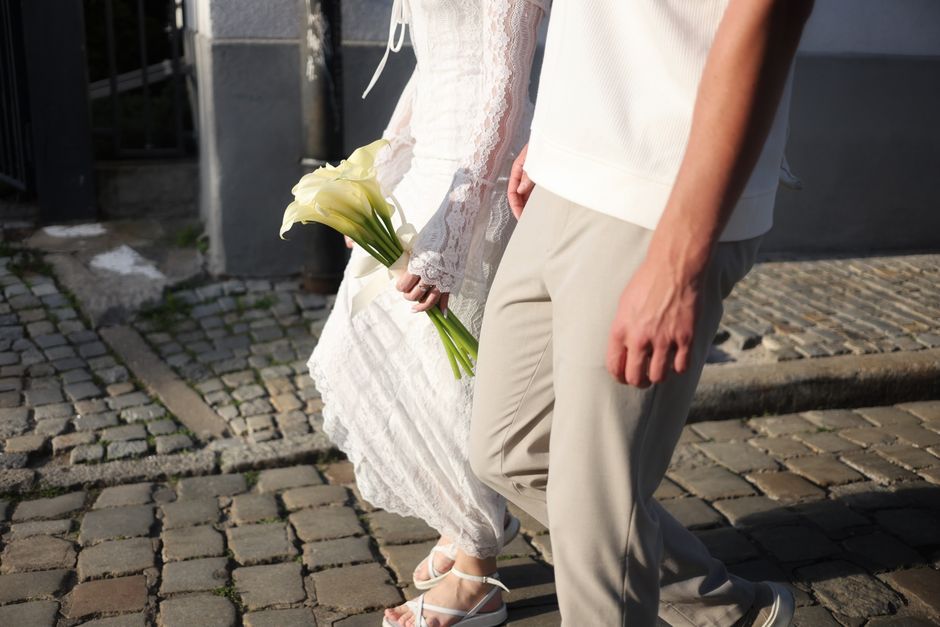 A couple walking on cobblestone street in Wrocław, Poland with calla lilies and summer attire.