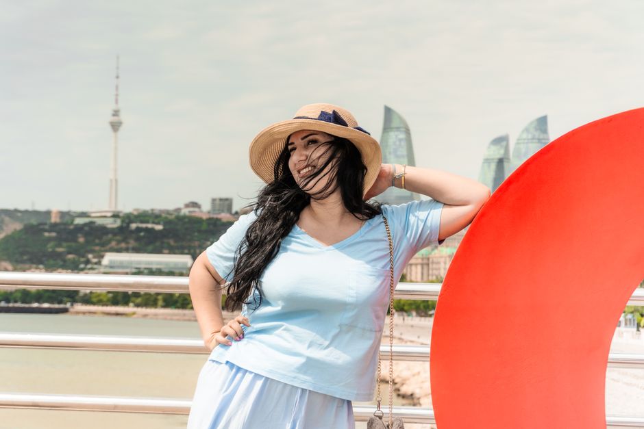 Young woman smiling by Baku Flame Towers and TV Tower in summer.