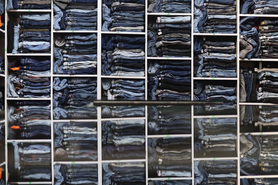 Organized display of folded jeans on shelves in a retail clothing store.