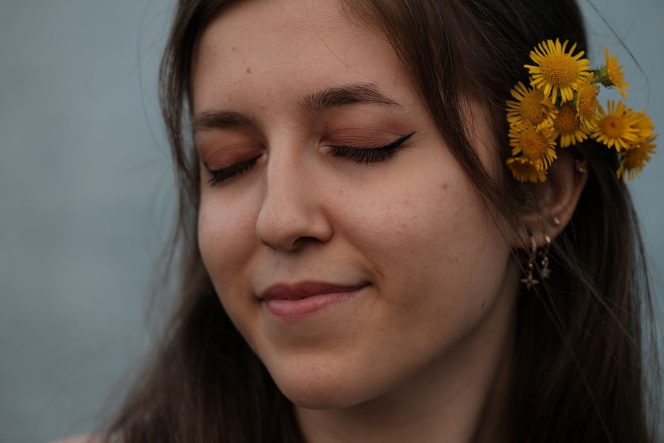 Serene portrait of a woman with dandelions in her hair and eyes closed, exuding peace and 