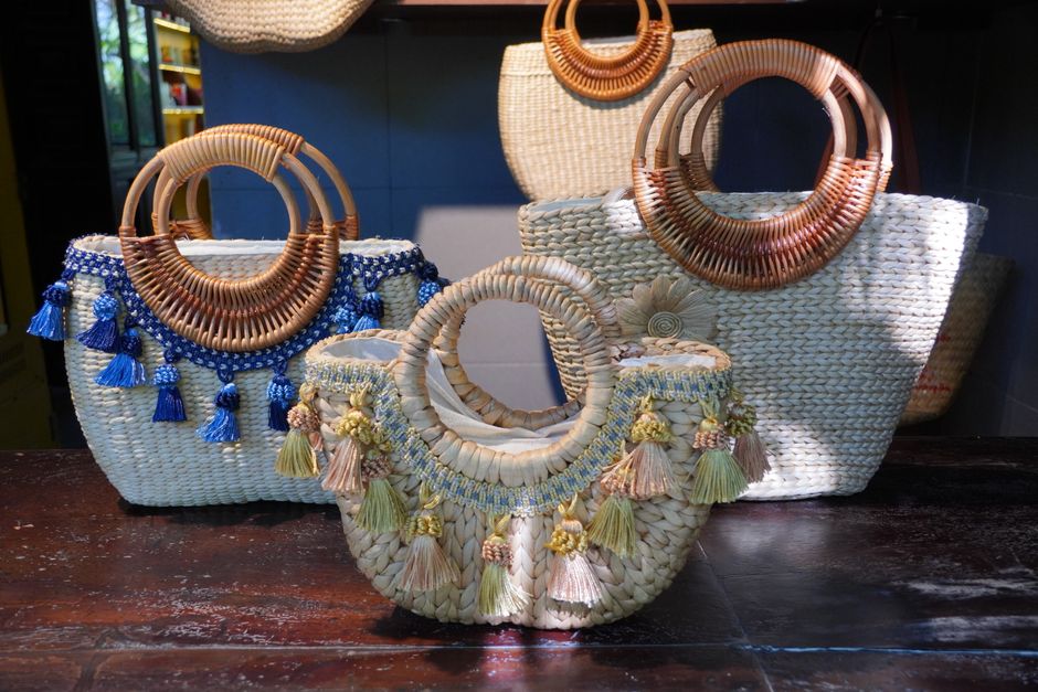 A collection of beautifully handcrafted straw baskets with detailed beadwork and tassels on display indoors.