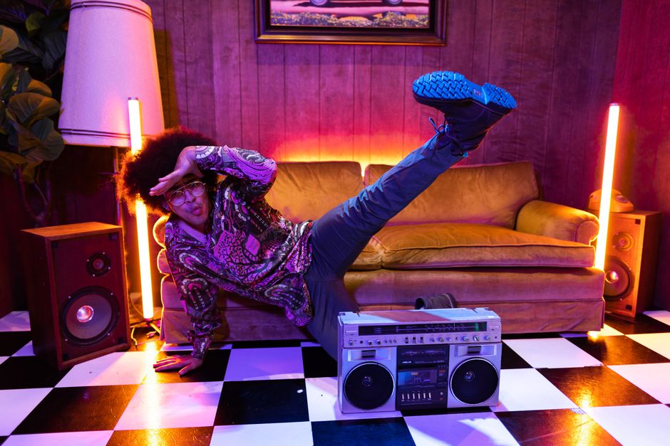 A vibrant retro-themed studio scene featuring a person dancing energetically with a vintage boom box.