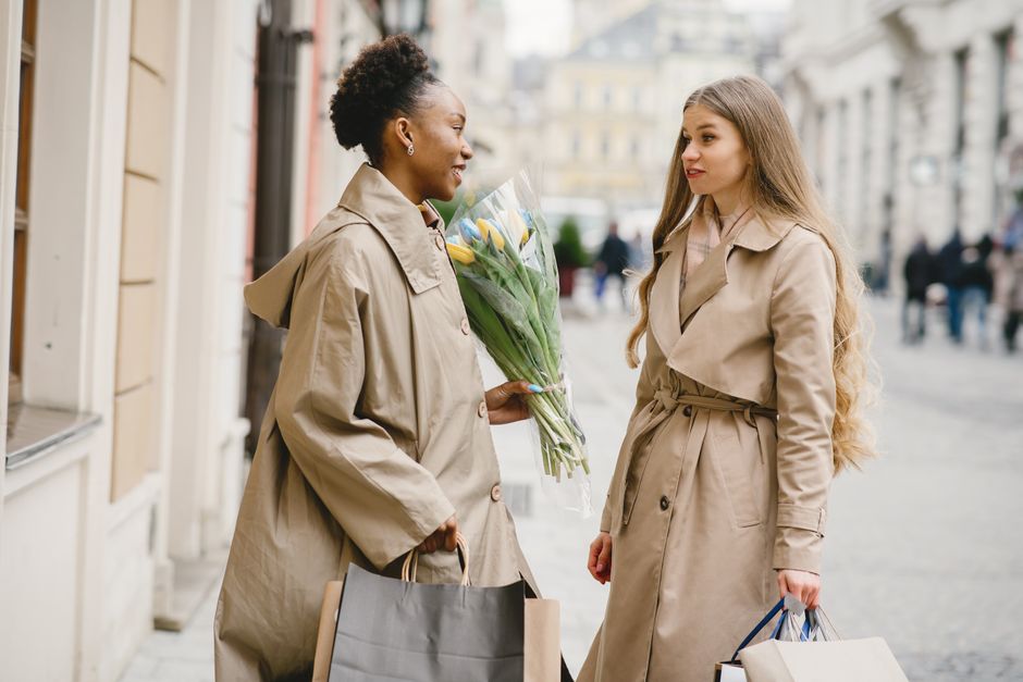 Two women engaging in conversation outdoors, enjoying a shopping day.
