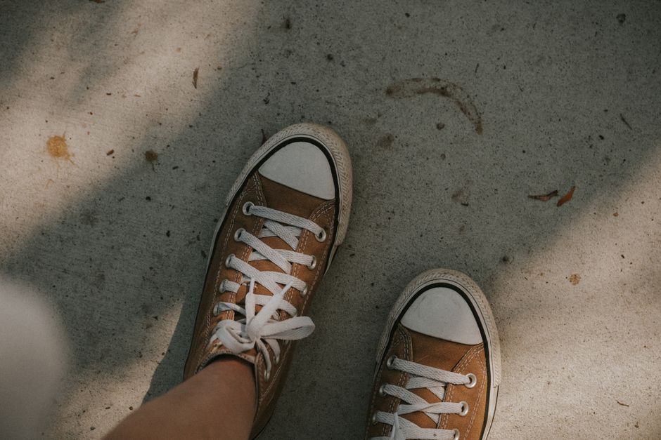 Brown sneakers on a sunlit concrete surface, capturing casual style.