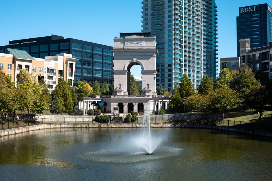 A scenic view of the Millennium Gate with reflections in a fountain, surrounded by Atlanta's cityscape.