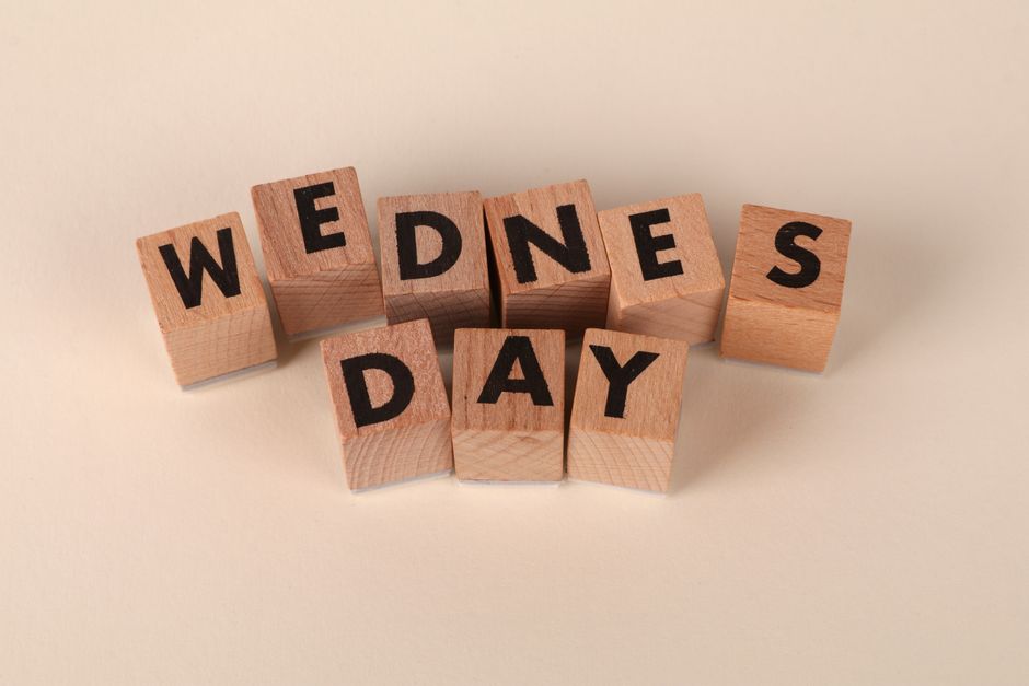 Wooden blocks arranged to spell Wednesday on a plain beige background, ideal for calendar 