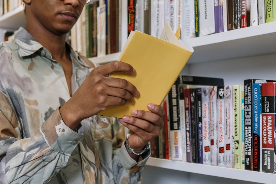 A young adult reading a yellow book in a library setting.
